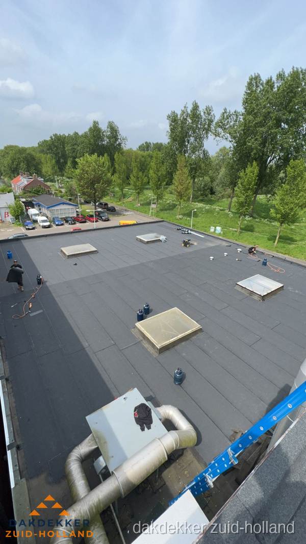 Dakdekker aan het werk op groot plat dak met bitumen in Zuid-Holland Dakdekker aan het werk op groot plat dak met bitumen in Zuid-Holland